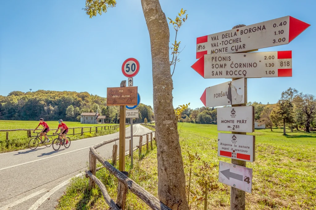 Incrocio su cui affacciano una serie di cartelli tra cui "via degli alpini", "val della Borgogna", "Peonis", "Forgar", "Monte Prat".