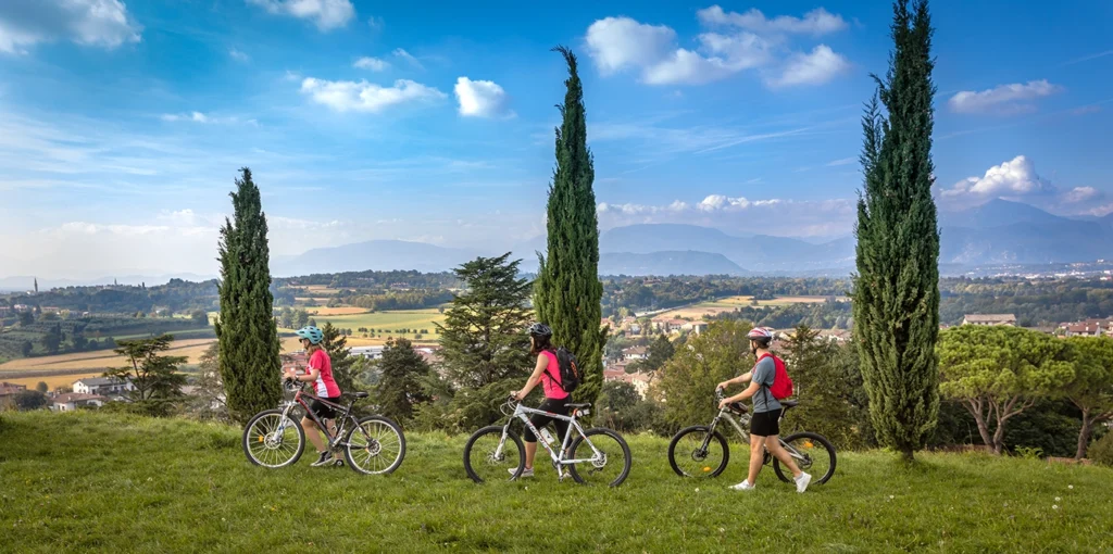 Tre ciclisti percorrono un prato, sullo sfondo il tipico panorama collinare