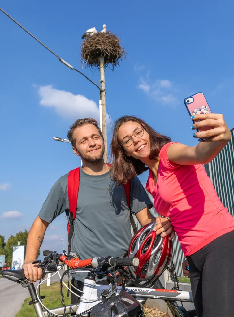 Due ragazzi si scattano una foto di fronte il nido di una cicogna